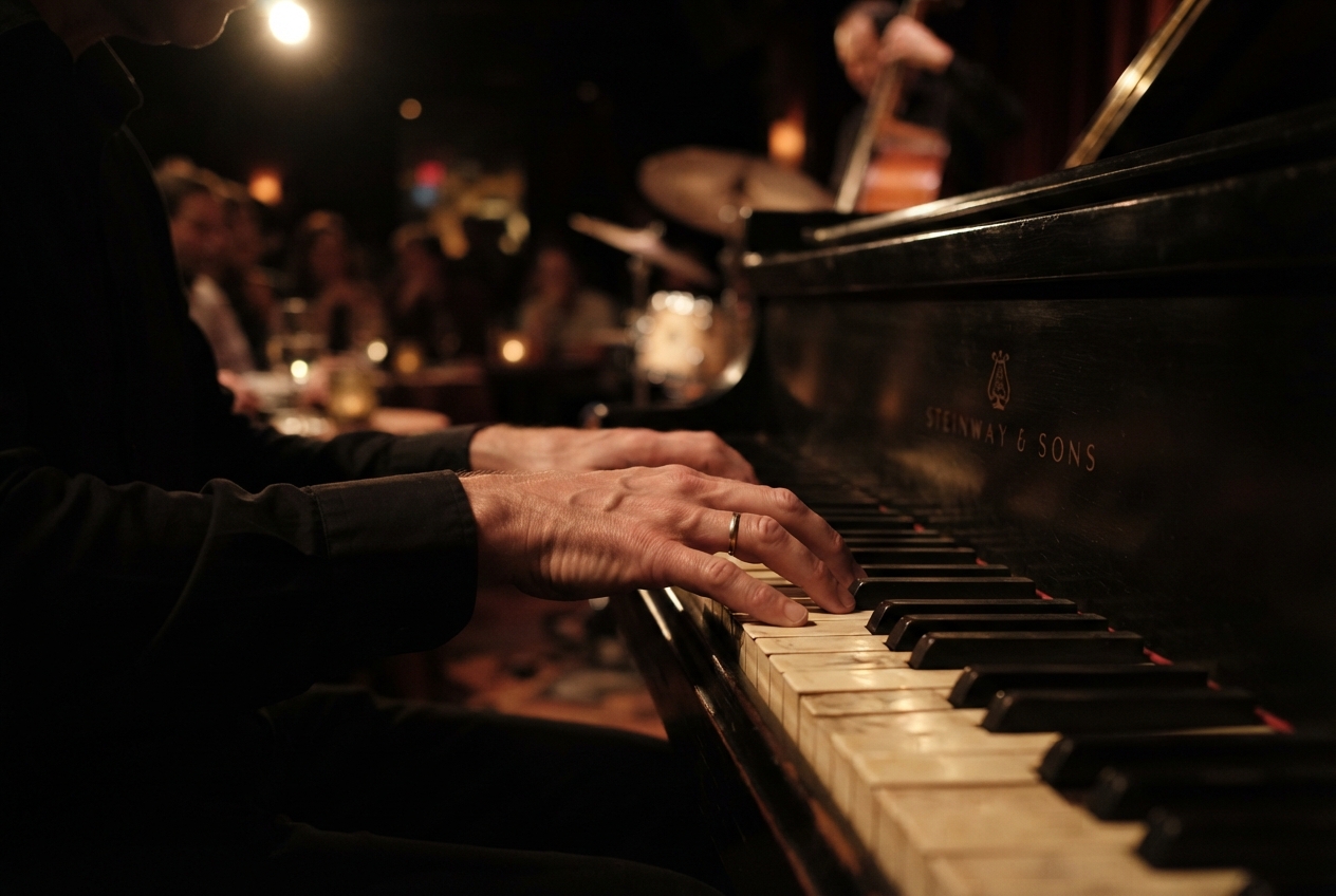 A pianist's hands on the keys of a grand piano in a dim jazz club